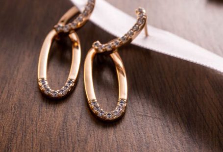 Fashion Staples - Two gold earrings with diamonds on a wooden table