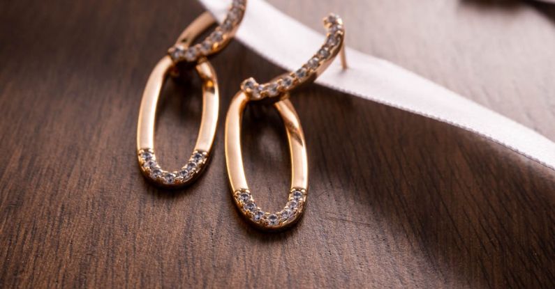 Fashion Staples - Two gold earrings with diamonds on a wooden table