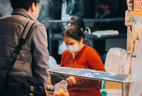 Bulk Buying - A woman in a face mask is standing at a food stand