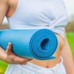Yoga Mat - Woman Standing and Holding Blue Yoga Mat