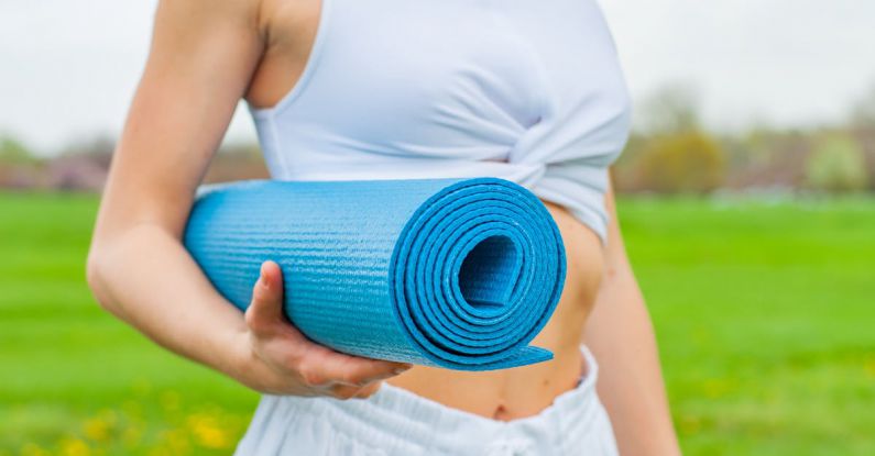 Yoga Mat - Woman Standing and Holding Blue Yoga Mat