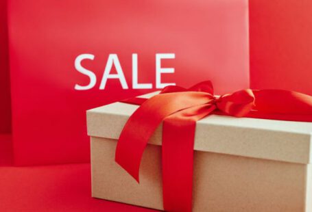 Luxury Deals - Cardboard Box with Red Ribbon Beside A Sale Sign